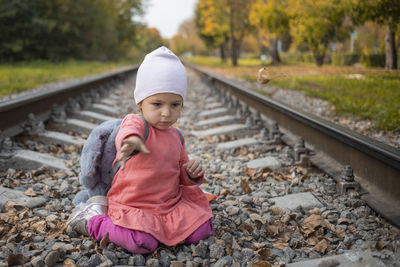 Little girl sitting on the train tracks in the forest