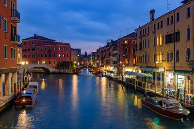 Boats in canal amidst buildings in city