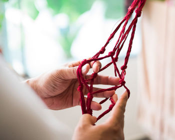 Close-up of hand weaving macramé hanging planter.