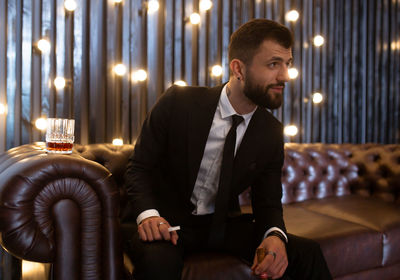 Young man sitting in illuminated room