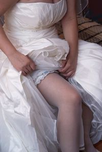 Low section of woman sitting on bed