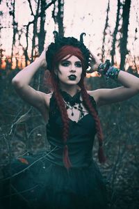 Portrait of woman standing by tree in forest