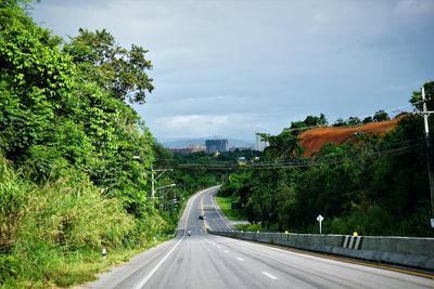 Road passing through city against sky