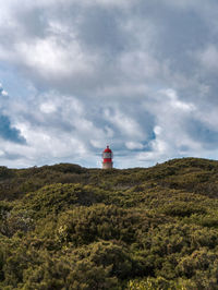 Lighthouse on road amidst buildings against sky