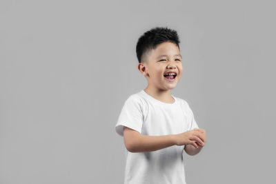 Portrait of smiling boy standing against white background