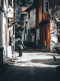 People walking on footpath amidst buildings in city