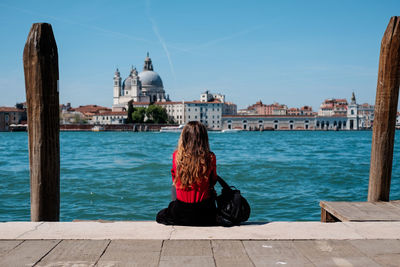 Rear view of woman sitting on pier at grand canal in old town