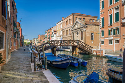 Boats moored in canal against clear sky