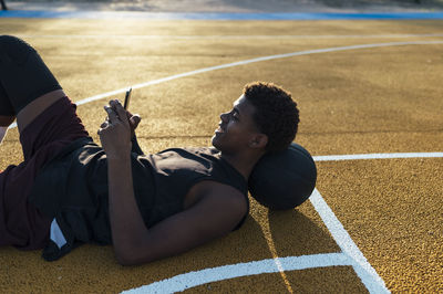 Side view african american sportsman in uniform looking at mobile