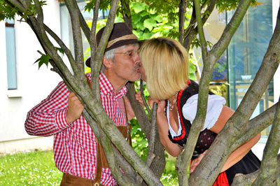 Couple kissing amidst tree branches in park