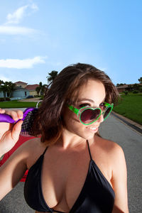 Portrait of smiling beautiful woman wearing heart shape sunglasses while combing hair