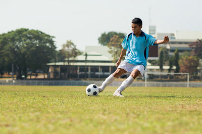 Full length of man playing soccer ball on grass