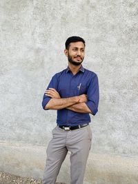 Portrait of young man standing against wall