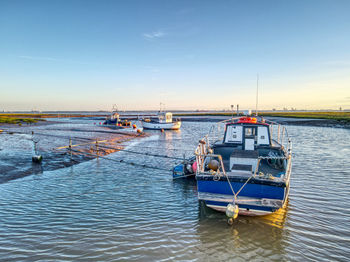 Fishing boats moored in sea against sky