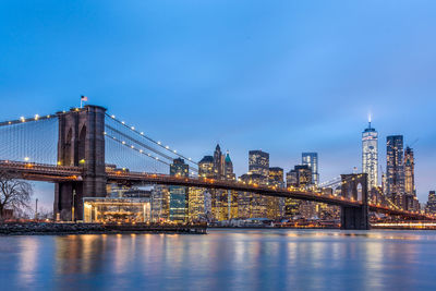 Illuminated bridge over river with city in background