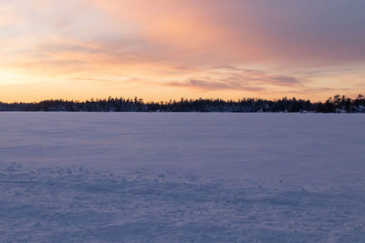 Scenic view of snow covered land against sky during sunset