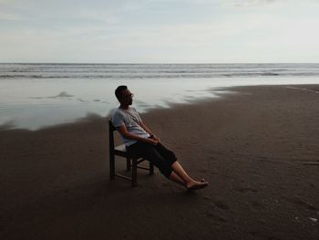 Young man sitting on chair at beach