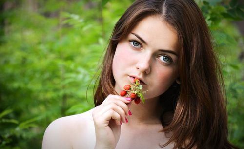 Portrait of young woman eating strawberry