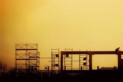 Silhouette construction site against clear sky during sunset