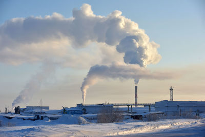 Smoke emitting from factory against sky