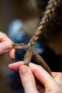 Cropped hands of woman braiding hair