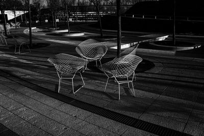 Empty chairs and table at sidewalk cafe in city