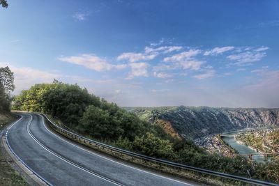 Scenic view of road by trees against sky