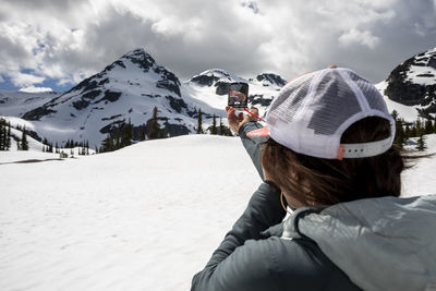 Anonymous woman using compass in snowy mountains
