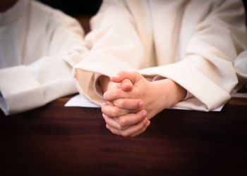 Midsection of person praying in church