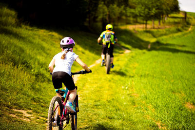 Rear view of man riding bicycle on field