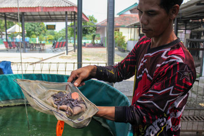 Man holding worms while standing outdoors