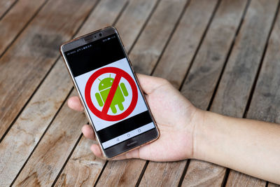 High angle view of person using mobile phone on wood