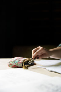 Close-up of hand on table against black background