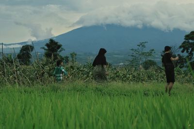 Family walking on field against sky