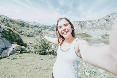 Portrait of young woman standing against mountain