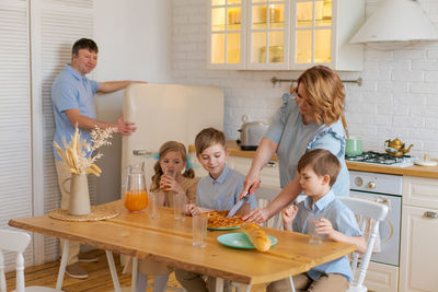 Happy family with three children has breakfast in kitchen in morning sitting