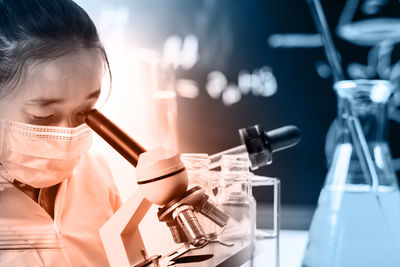 Close-up of female doctor looking in microscope in laboratory