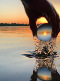Reflection of woman on lake during sunset