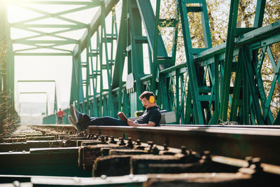 Full length of engineer reading book while sitting on railroad track