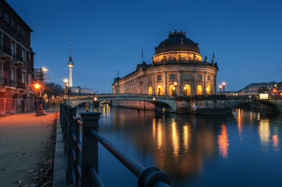 Bridge over river against sky in city at dusk