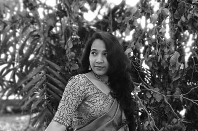 Portrait of young woman standing against trees