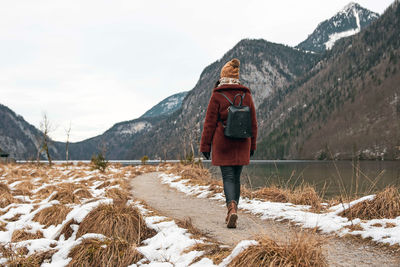 Young woman walking on a path by a lake. winter, snow, cold weather.