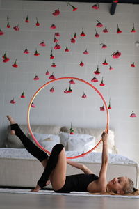 Little girl in sporty black clothes and leggings doing exercise with hoop on floor