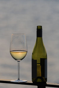 Close-up of wineglass with bottle on railing