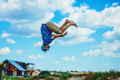 Low angle view of man jumping against sky