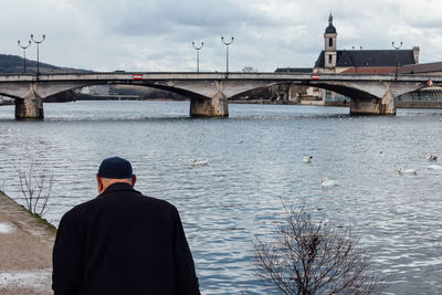 Rear view of man by river against sky