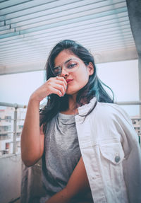 Portrait of beautiful young woman wearing eyeglasses while sitting on rooftop