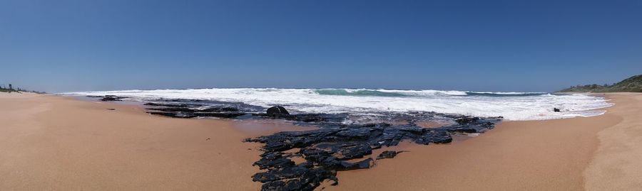 Scenic view of beach against clear blue sky