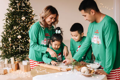 Asian family with two children in pajamas prepare festive food for the christmas holiday at home