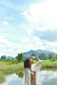 Rear view of woman looking at lake against sky